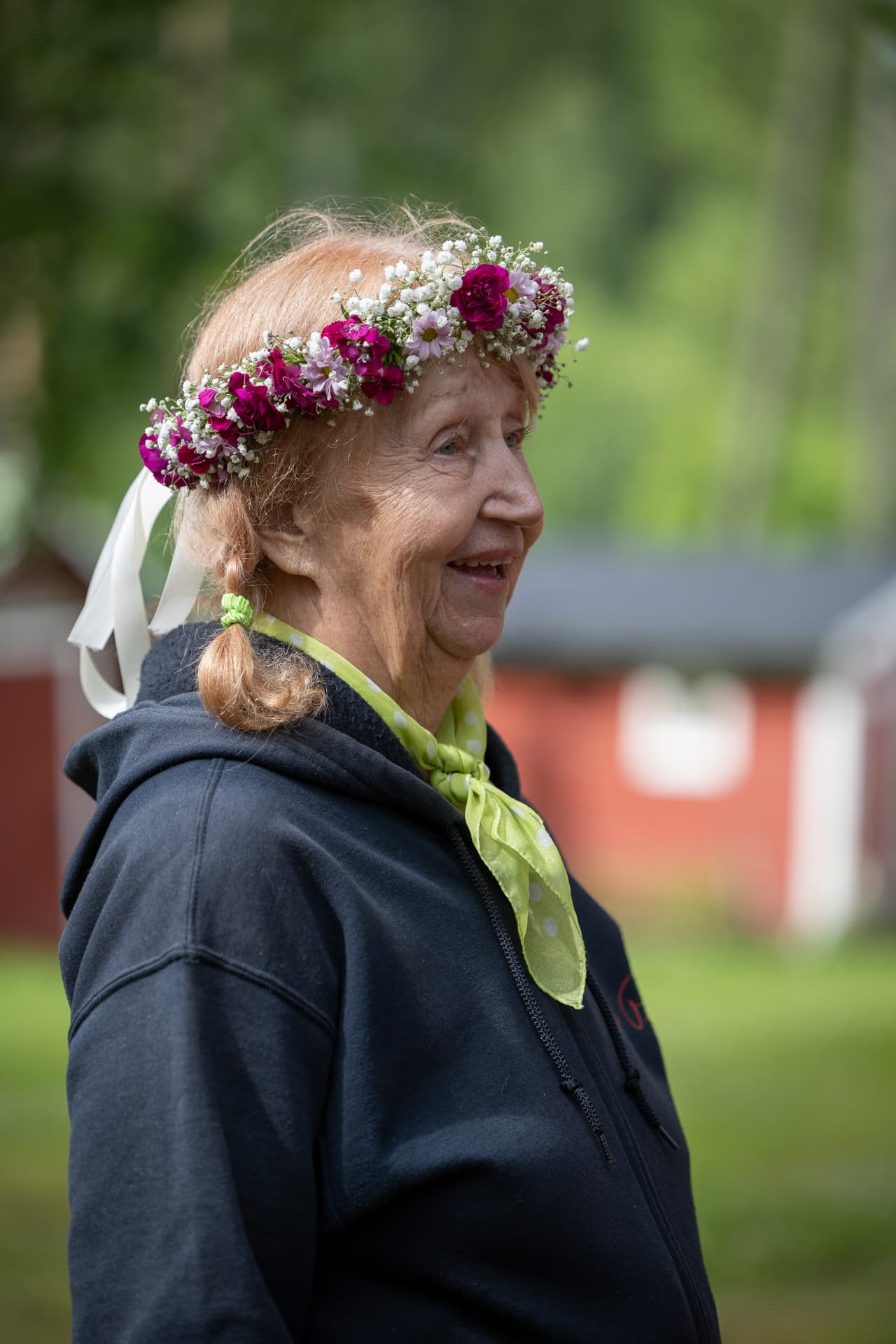 Marjatta hymyilee kukkaseppele päässään Elvis-tuvan pihalla