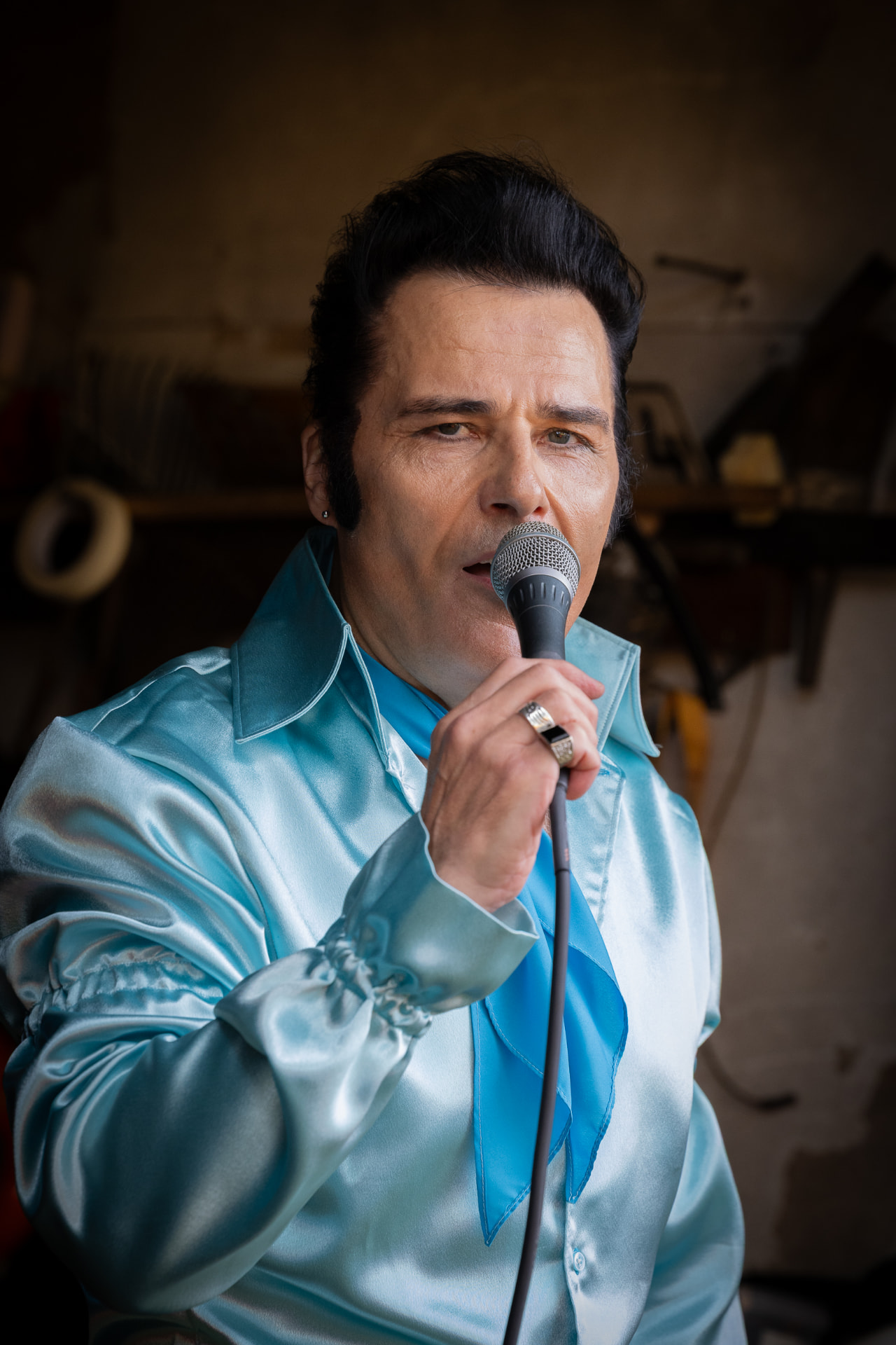 Lähikuva Elvis-esiintyjästä laulamassa mikrofoniin