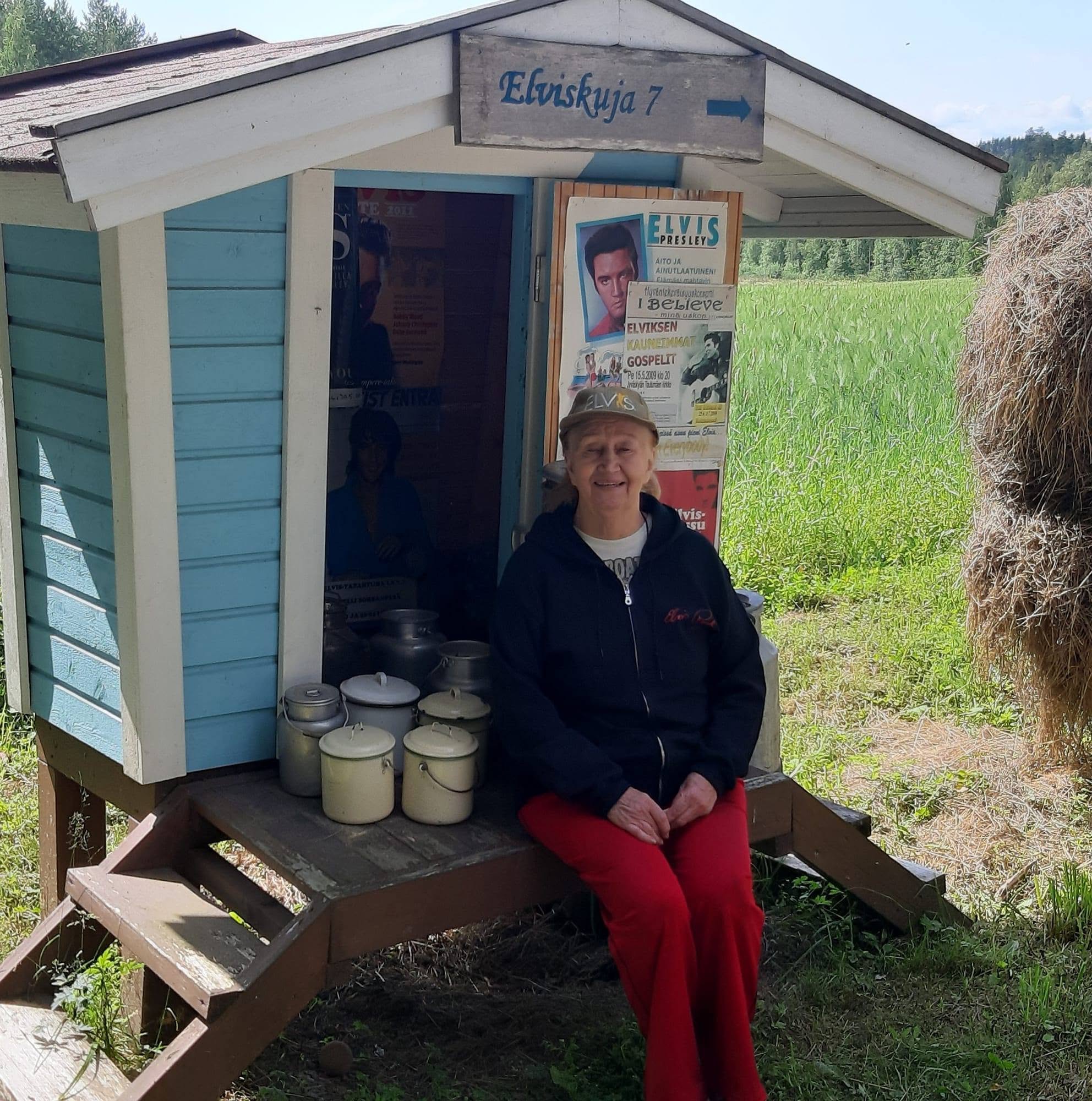 Marjatta Kinnunen istuu Elviskuja 7 -mökin portailla