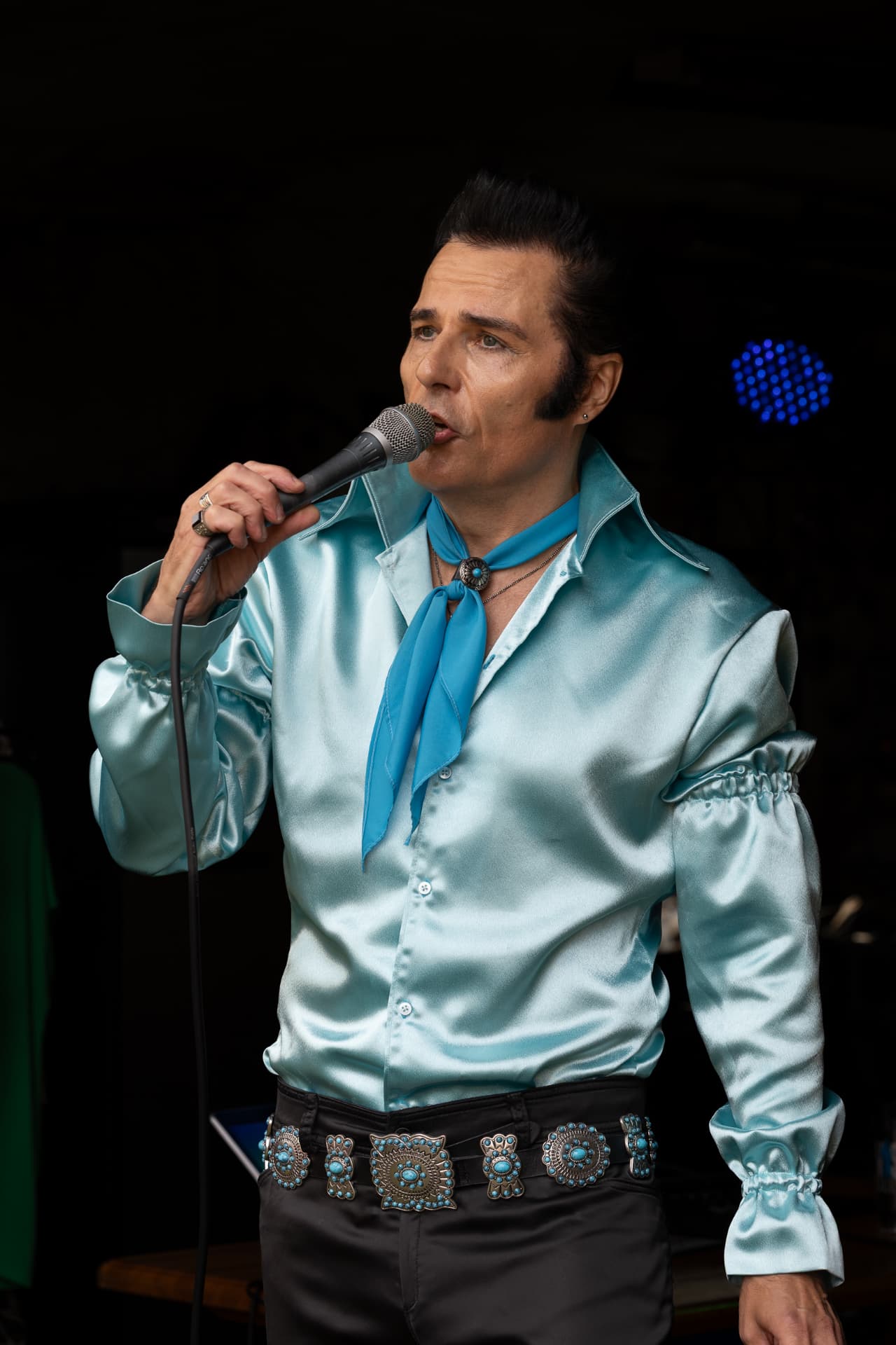 Elvis-esiintyjä laulaa lavalla sinisen valon loisteessa